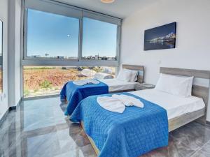 zwei Betten in einem Zimmer mit großen Fenstern in der Unterkunft Villa Manta Chrysos - Brand New Luxury 3 Bedroom Protaras Villa in Protaras + 14 Fotos