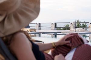 a woman is sitting next to a swimming pool at Queen Bee Luxury Villa- Sparto in Spárton