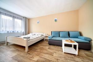 a bedroom with a bed and a blue couch at Penzion Zajíček in Zaječí
