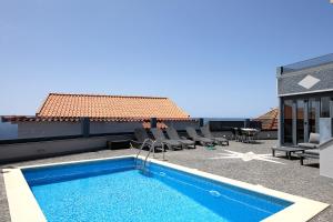una persona sentada en el tejado de una casa con piscina en ANGEL´S SUNSET, en Estreito da Calheta
