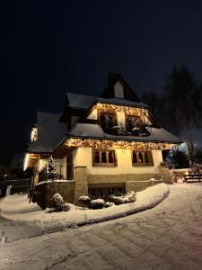a house with christmas lights on it in the snow at Willa Chrycówka - Jacuzzi, Basen, Sauna in Kościelisko