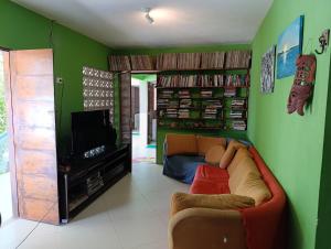 a living room with a couch and a tv at Praia, piscina e churrasco in Itamaracá