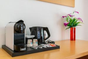 a coffee maker on a table with a vase of flowers at Catania Crossing B&B - Rooms & Comforts in Catania