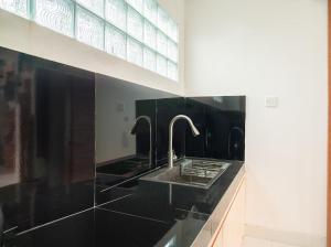 a black bathroom with a sink and two faucets at Aspen bali nusa dua in Nusa Dua