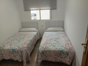 two beds in a small room with a window at Arenales Beach in Arenales del Sol +6 photos