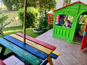a child playing in a toy house with a bench at Castelletto Verde in Bari Sardo