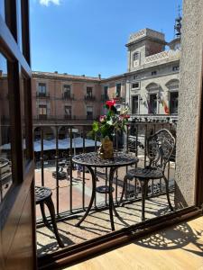 a balcony with a table and chairs and a vase of flowers at El Balcón del Mercado Chico in Avila
