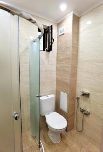 a bathroom with a toilet and a glass shower stall at Cabacum Pleasure Beachfront Apartments in Varna City