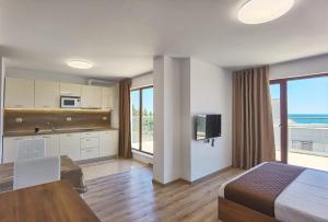 a bedroom with a bed and a kitchen with a view at Cabacum Pleasure Beachfront Apartments in Varna City