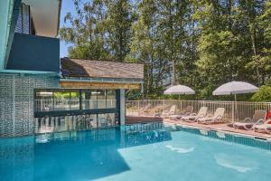 a swimming pool with chairs and umbrellas at Résidence Odalys Isatis in Chamonix