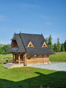 a large log cabin with a black roof at Domek u Beaty in Dzianisz