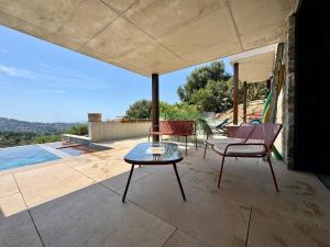 a patio with chairs and a table and an umbrella at Villa la Caladine in a quiet location in Bormes-les-Mimosas