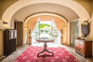 een kamer met een tafel en een rood tapijt bij Hotel Il Campanile in Cherasco