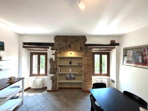 a living room with a table and a brick wall at Residenza La Rocca 1227 - Borgo Castello di Serravalle in Castello di Serravalle