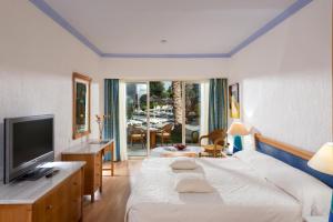a hotel room with a bed and a television at Paphos Gardens Holiday Resort in Paphos City +11 photos