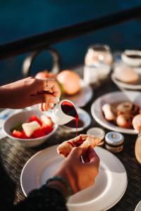 a table with plates of food and a person pouring sauce at Verdi St George's Bay Marina in St. Julianʼs