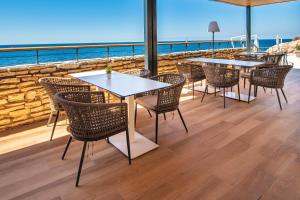 a patio with tables and chairs and the ocean at Arena Verudela Beach in Pula