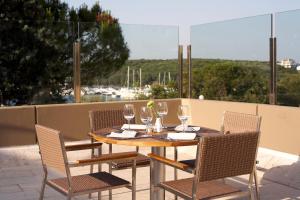 a wooden table with chairs and wine glasses on a patio at Arena Verudela Beach in Pula