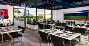 a restaurant with white tables and black chairs at Arena Verudela Beach in Pula