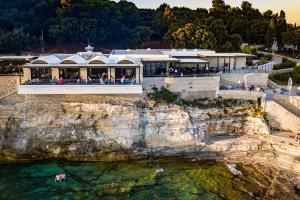 a building on a cliff next to the water at Arena Verudela Beach in Pula