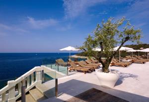 a deck with chairs and a tree and the ocean at Arena Verudela Beach in Pula