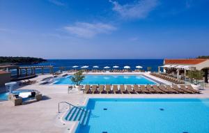 a pool with chairs and the ocean in the background at Arena Verudela Beach in Pula