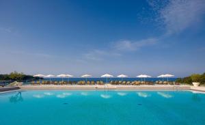 a large swimming pool with chairs and umbrellas at Arena Verudela Beach in Pula