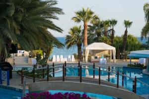 a pool at a resort with palm trees at Mediterranean Beach Hotel in Limassol