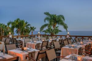 a restaurant with tables and chairs next to the ocean at Mediterranean Beach Hotel in Limassol