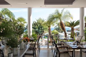 a restaurant with tables and chairs and palm trees at Mediterranean Beach Hotel in Limassol