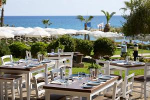 a group of tables and chairs with the ocean in the background at Mediterranean Beach Hotel in Limassol