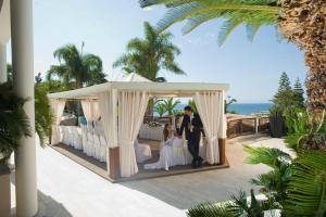 a bride and groom standing under a gazebo at Mediterranean Beach Hotel in Limassol