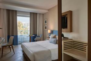 a hotel room with a bed and a balcony at Mediterranean Beach Hotel in Limassol