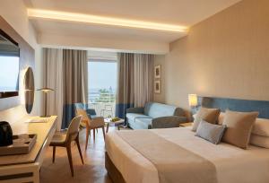 a hotel room with a bed and a living room at Mediterranean Beach Hotel in Limassol