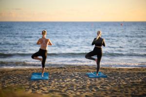 two women are doing yoga on the beach at Mediterranean Beach Hotel in Limassol