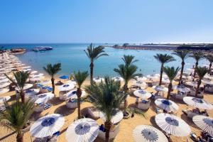 plaża z wieloma białymi parasolami i palmami w obiekcie Swiss Inn Resort Hurghada w mieście Hurghada