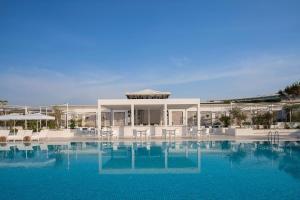 a large swimming pool with chairs and a building at Voyage Belek Golf & Spa Hotel in Belek