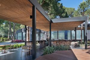 an outdoor patio with tables and chairs and trees at Voyage Belek Golf & Spa Hotel in Belek