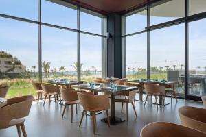 a restaurant with tables and chairs and large windows at Voyage Belek Golf & Spa Hotel in Belek