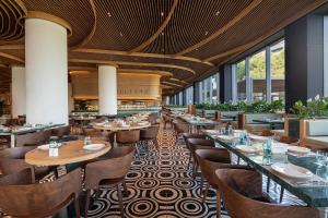 a restaurant with wooden tables and chairs and windows at Voyage Belek Golf & Spa Hotel in Belek