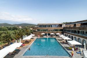 een groot zwembad met witte parasols en een gebouw bij Blue Dolphin Hotel in Metamorfosi