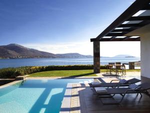 ein Swimmingpool mit Liegen und Blick aufs Wasser in der Unterkunft Grand Resort Lagonissi in Lagonisi + 73 Fotos