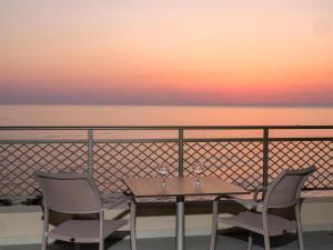 a table and chairs on a balcony with a sunset at Nana Golden Beach All Inclusive Resort & Spa in Hersonissos
