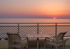 a table and two chairs with a sunset in the background at Nana Golden Beach All Inclusive Resort & Spa in Hersonissos