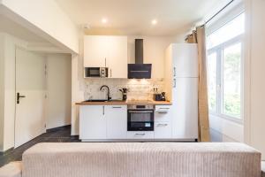 a kitchen with white cabinets and a refrigerator at Hôtel Lefort - Le Cocon Harmonieux in Guingamp