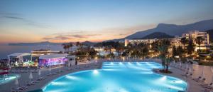 a large swimming pool with chairs and a city at Mirage Park Resort - Premium All Inclusive in Kemer