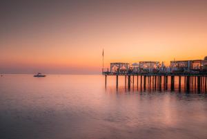 a pier on the water at sunset with a boat at Sidera Kirman Premium - Ultra All Inclusive in Okurcalar