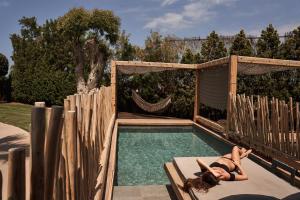 una mujer tumbada en un banco junto a una piscina en NEMA Design Hotel & Spa - Adults Only, en Hersonissos