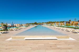 a large swimming pool with lounge chairs and tables at Arena Grand Kazela Camping Homes in Medulin