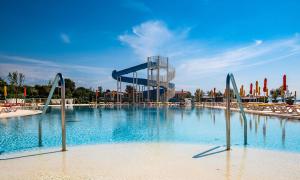 a large swimming pool with a building in the background at Arena Grand Kazela Camping Homes in Medulin